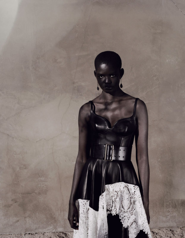 BLACK LEATHER CORSETED DRESS WITH ASYMMETRIC DRAPED SKIRT WITH IVORY ENDANGERED LACE, BLACK LEATHER BELT, GOLD AND GARNET EARRINGS Photography Alex Black - Alexander McQueen special, Lampoon Issue 20